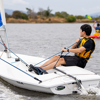 A boy doing performance sailing at shoreline lake
