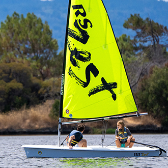 Two kids in the water with their boat.