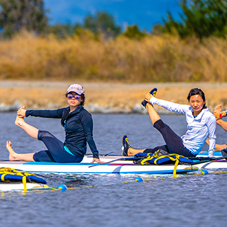 woman doing sup yoga at shoreline lake.