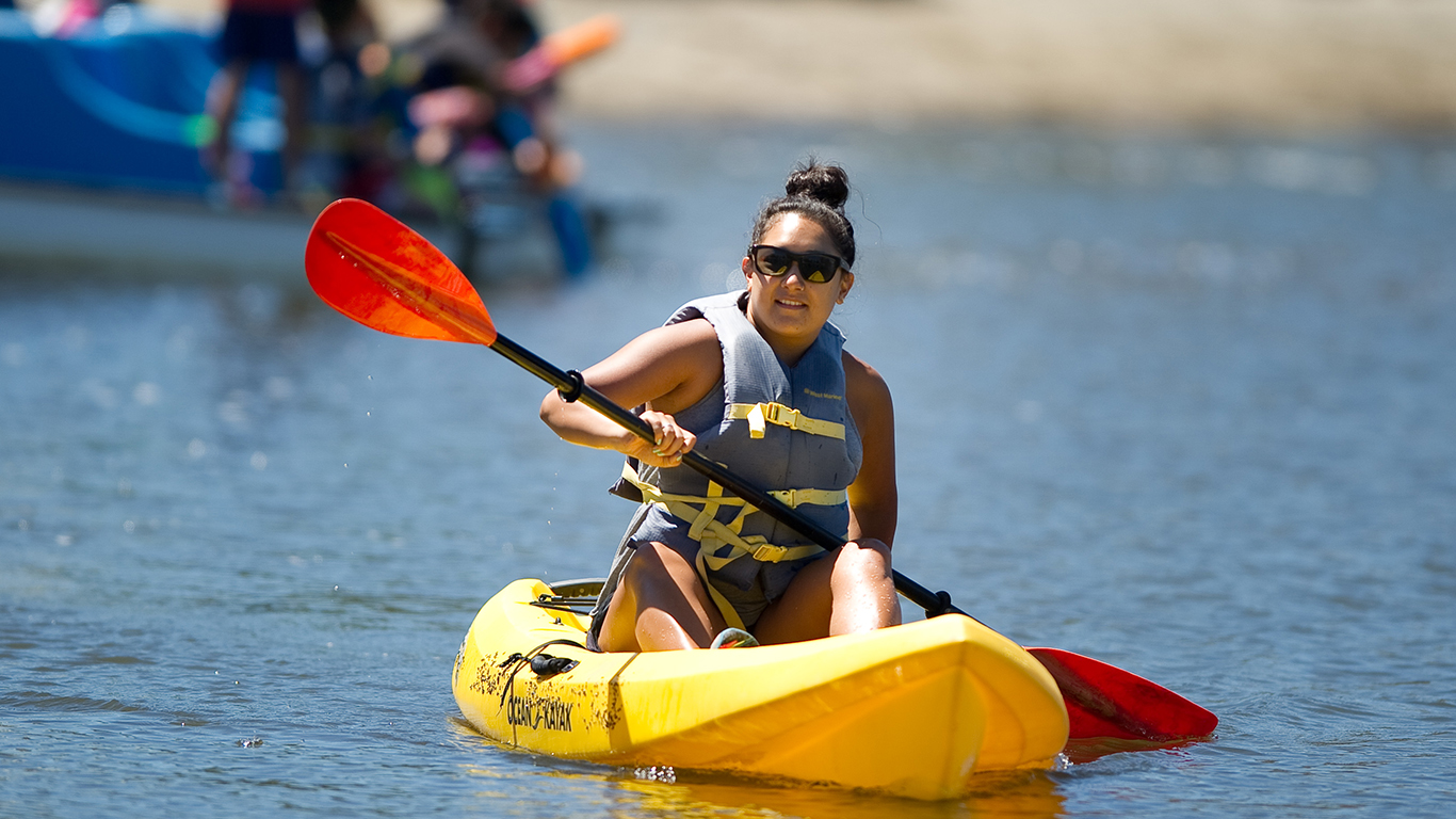 A woman in a kayak on shoreline lake.