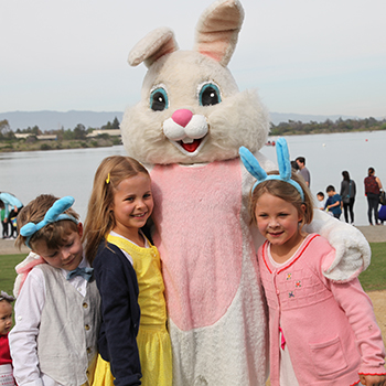 THe easter bunny standing with a group of kids at shoreline lake