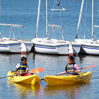 A young boy and girl in separate kayaks.