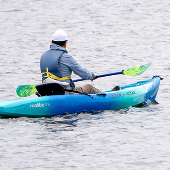 A man rowing away in an ocean kayak
