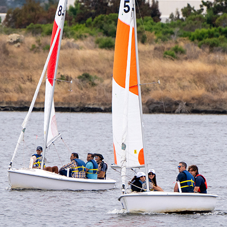 Two boats filled with people on shoreline lake.